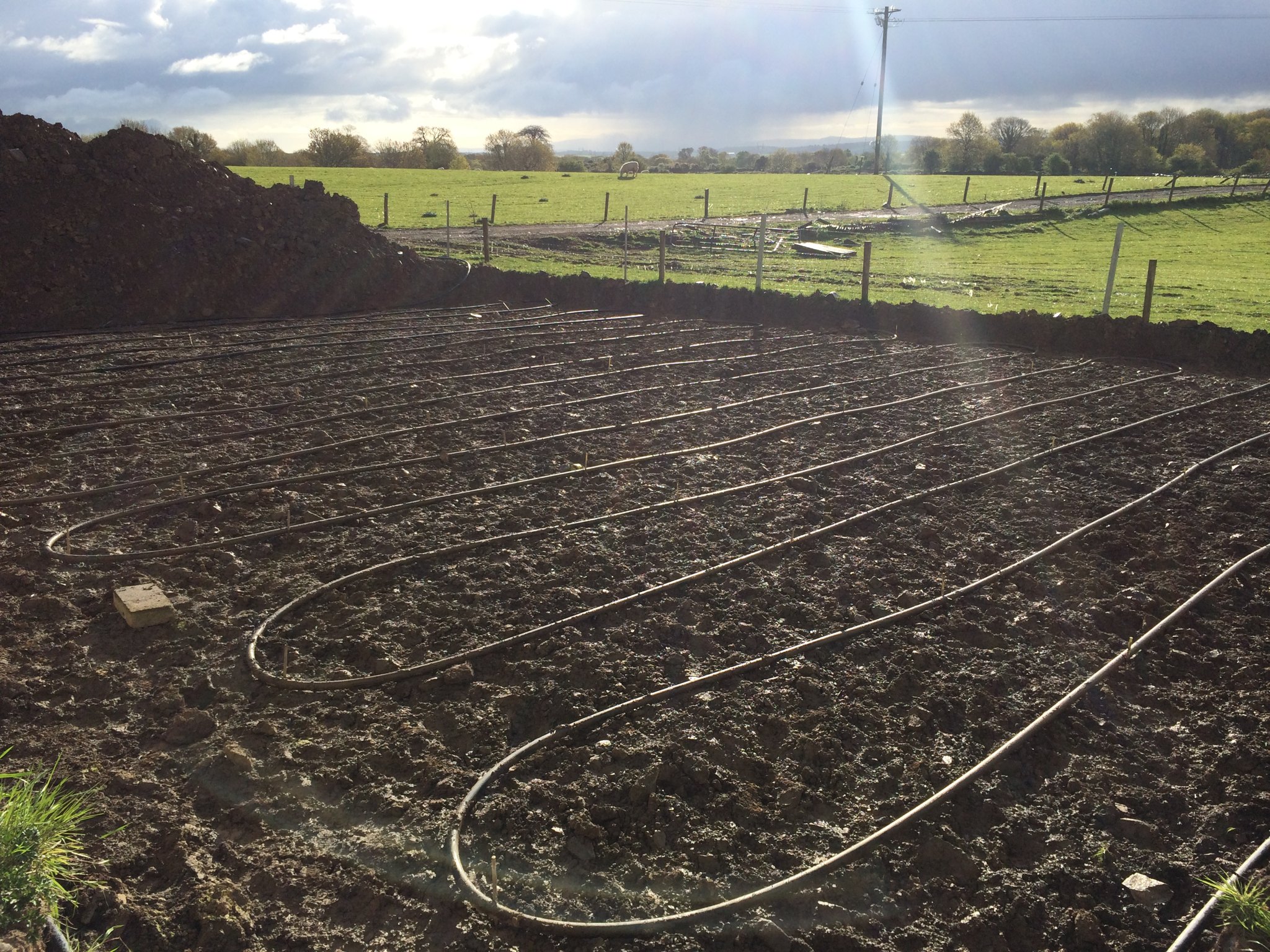 Ground source collector pipes laid in trenches across a field
