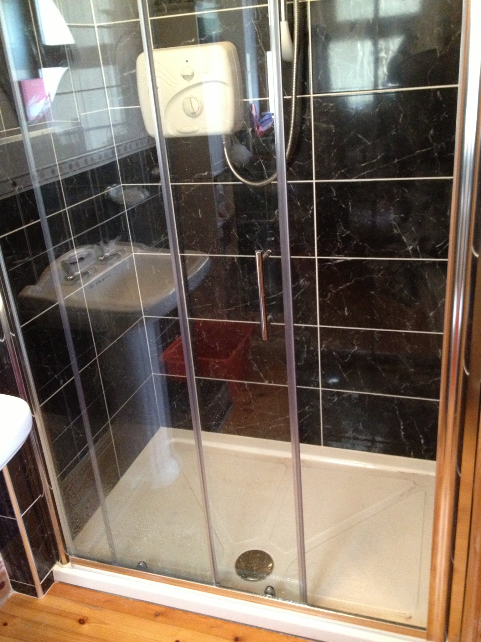 Shower enclosure with dark wall tiles and a glass door