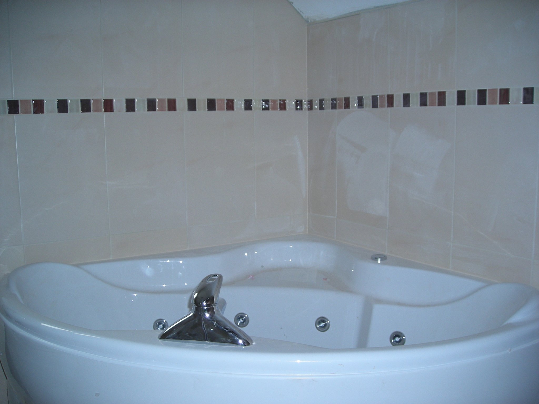 Corner whirlpool bath with a mosaic tile border